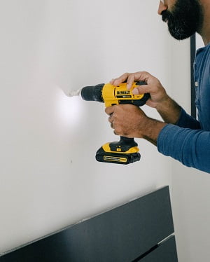 man drilling hole on wall